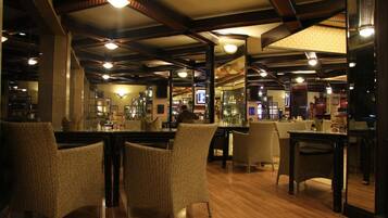Een restaurantinterieur met hoge plafonds, zichtbare balken en rieten stoelen.