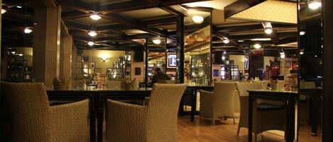 A restaurant interior with high ceilings, exposed beams, and wicker chairs.