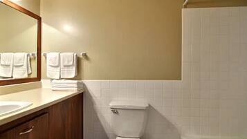 A bathroom with a toilet, sink, and bathtub. There are towels hanging on the wall.