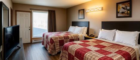Habitación de hotel con dos camas, un televisor, una puerta al exterior y un cuadro en la pared.