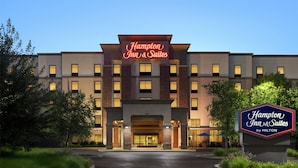 A Hampton Inn & Suites by Hilton building with a prominent sign, a well-lit entrance, and a landscaped driveway. - Hampton Inn & Suites Pittsburgh/Harmarville (Pittsburgh)