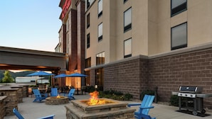 An outdoor patio with stone seating, a fire pit, and a grill area. - Hampton Inn & Suites Pittsburgh/Harmarville (Pittsburgh)