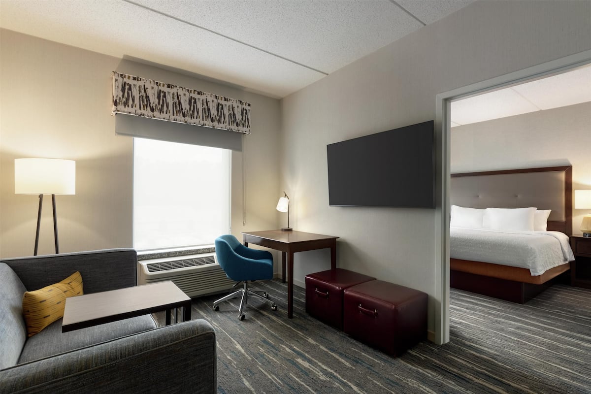 A hotel room with a sofa, desk, chair, and a bed.