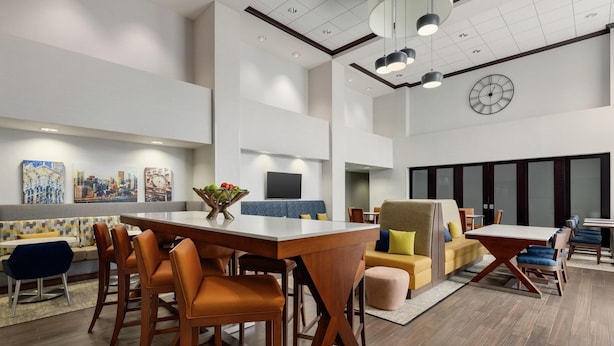 A modern interior with a dining area, seating, and a clock on the wall. - Hampton Inn & Suites Pittsburgh/Harmarville (Pittsburgh)