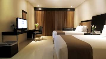 Una habitación de hotel moderna con una televisión de pantalla plana, un escritorio, dos camas y un amplio ventanal con cortinas.