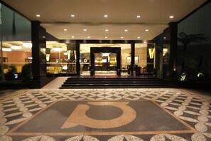 Entrada de un hotel con un piso de diseño geométrico y un gran símbolo 'P'.