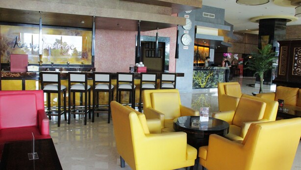 A hotel lobby with yellow seating, a reception desk, and a bar area. - Hotel Aria Gajayana Malang (Malang)