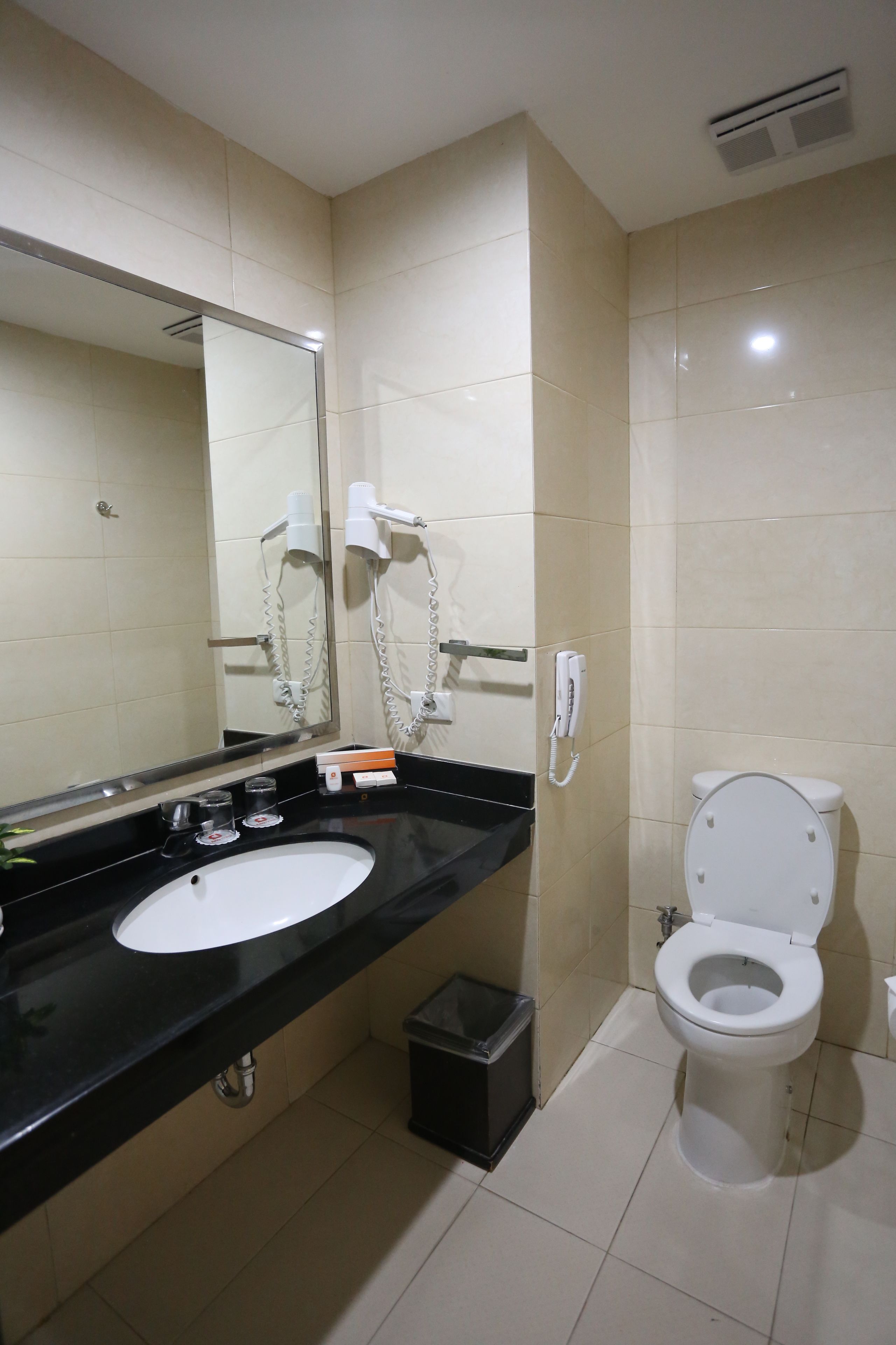 A bathroom with a black sink, a white toilet, and a mirror.