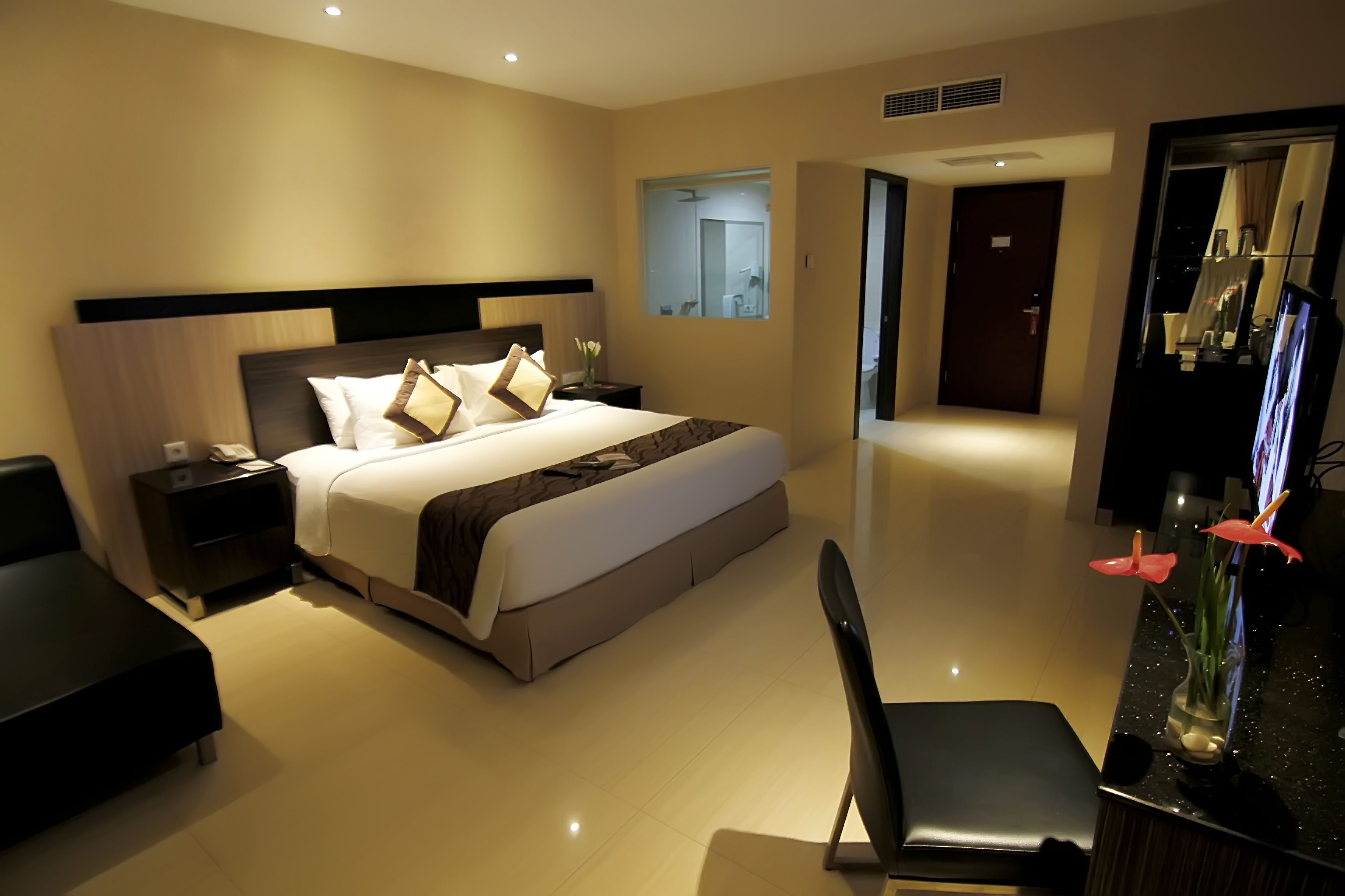 Una habitación de hotel moderna con una cama grande, mesitas de noche, un escritorio y una silla.