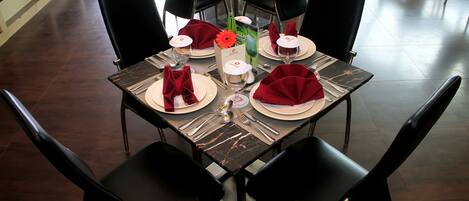 Una mesa de comedor con servilletas rojas, platos blancos y cubiertos.