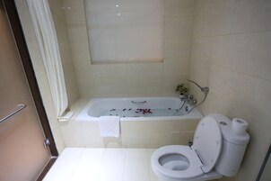 Un baño con bañera, inodoro y cortina de ducha.