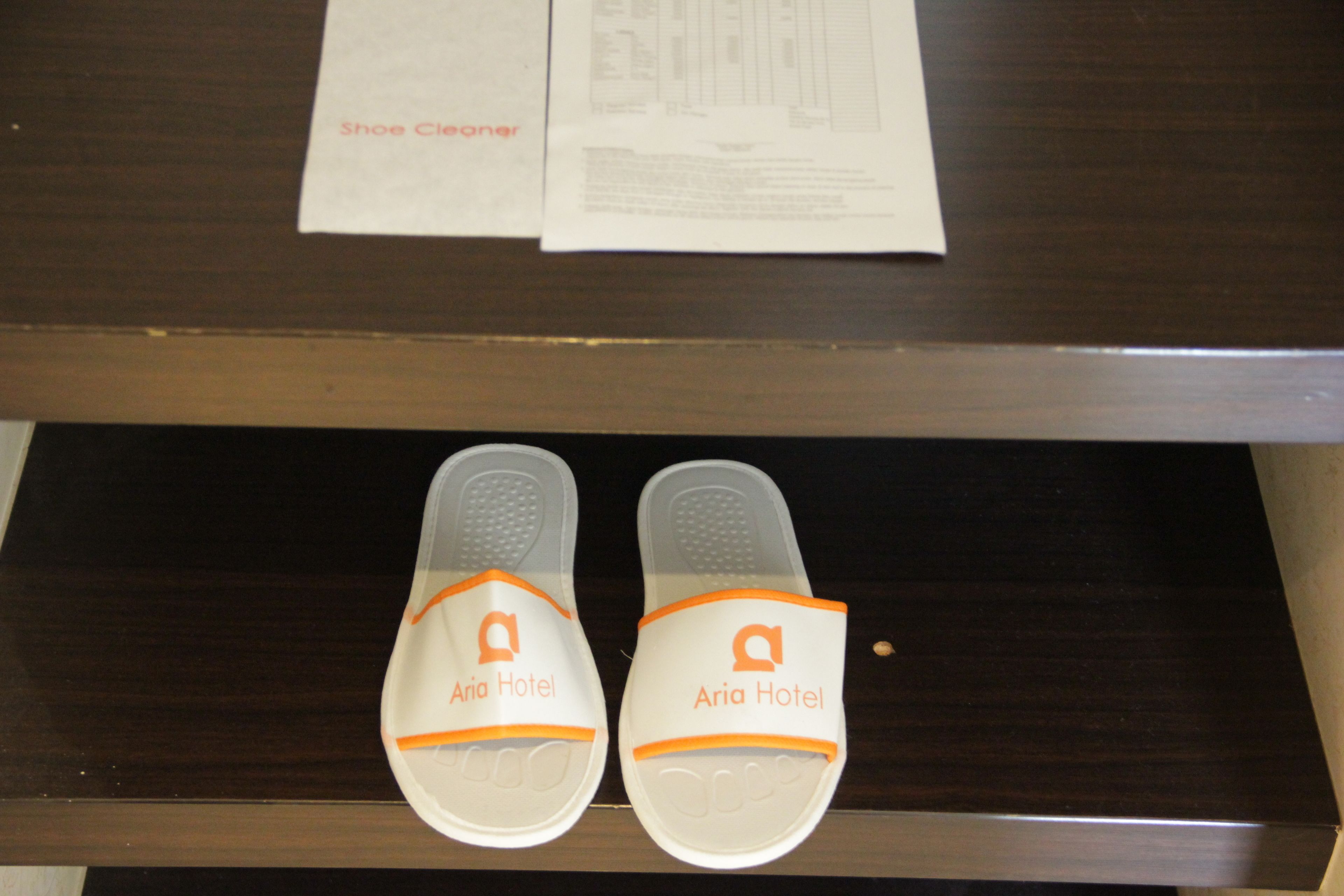 Une paire de chaussons ornés du logo de l’hôtel Aria, posée sur une surface en bois.
