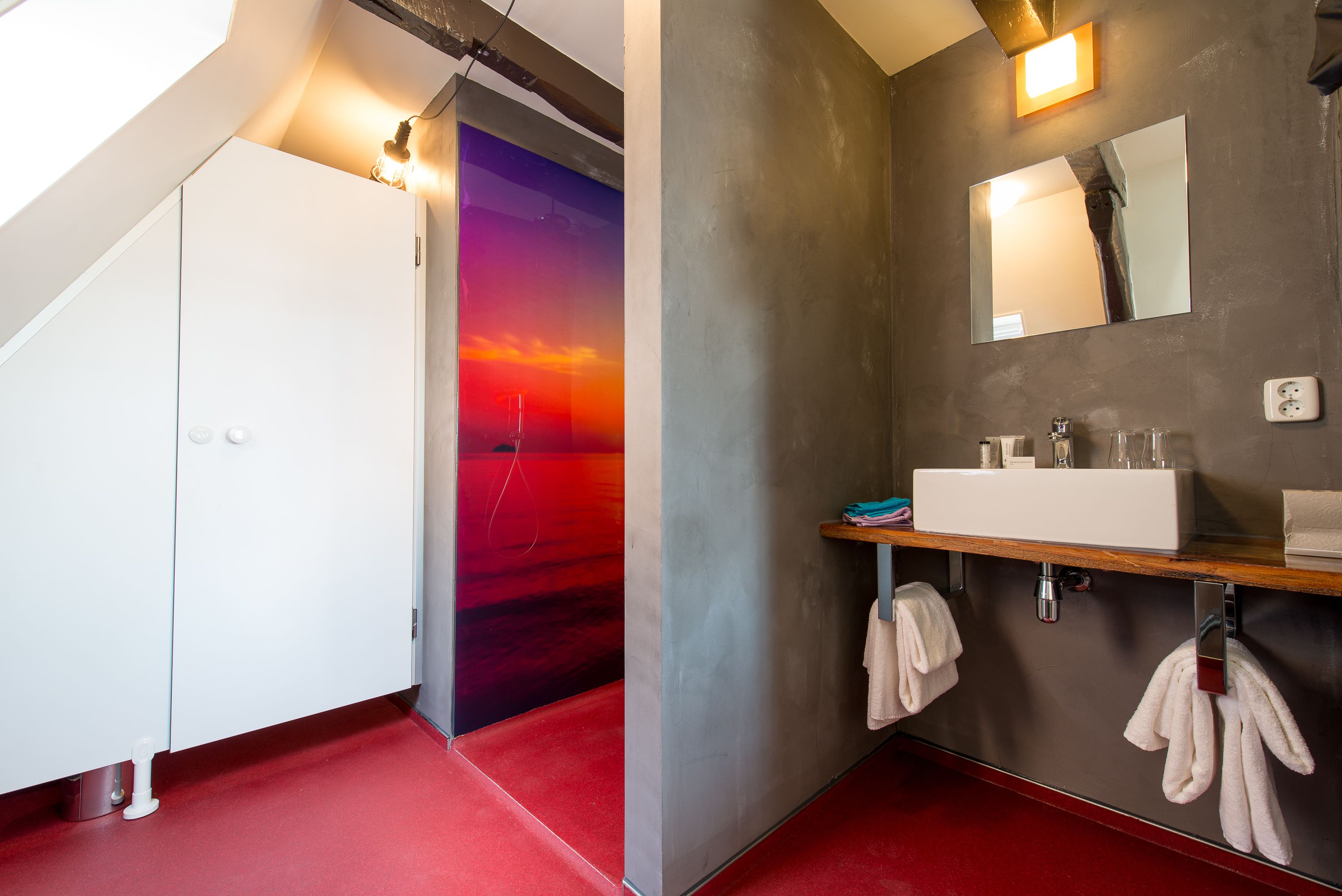 A modern bathroom with a white vanity, a large mirror, and a red carpeted floor.