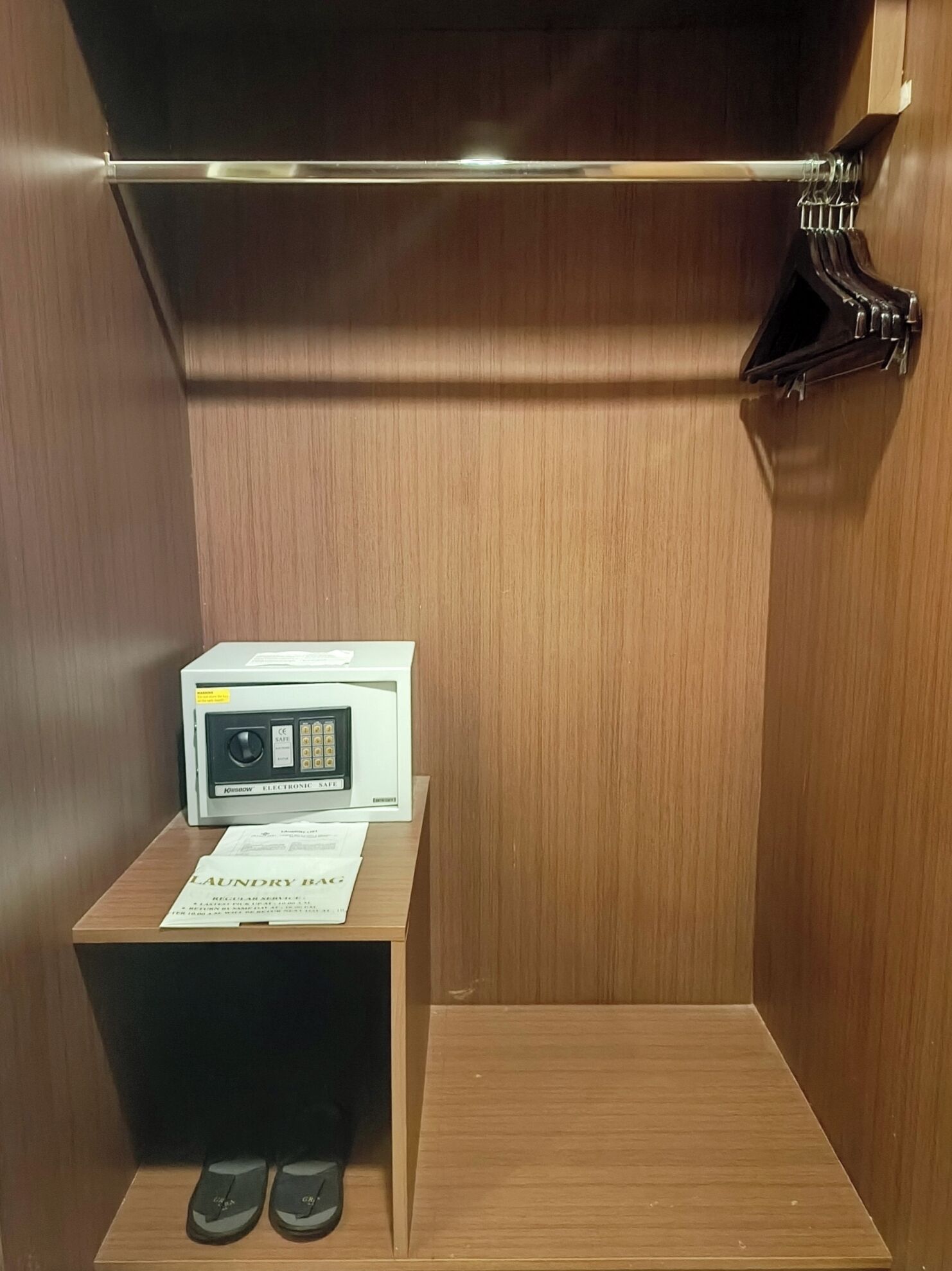 A wooden closet with a microwave on top, a pair of sandals on the floor, and a "Laundry Bag" sign.