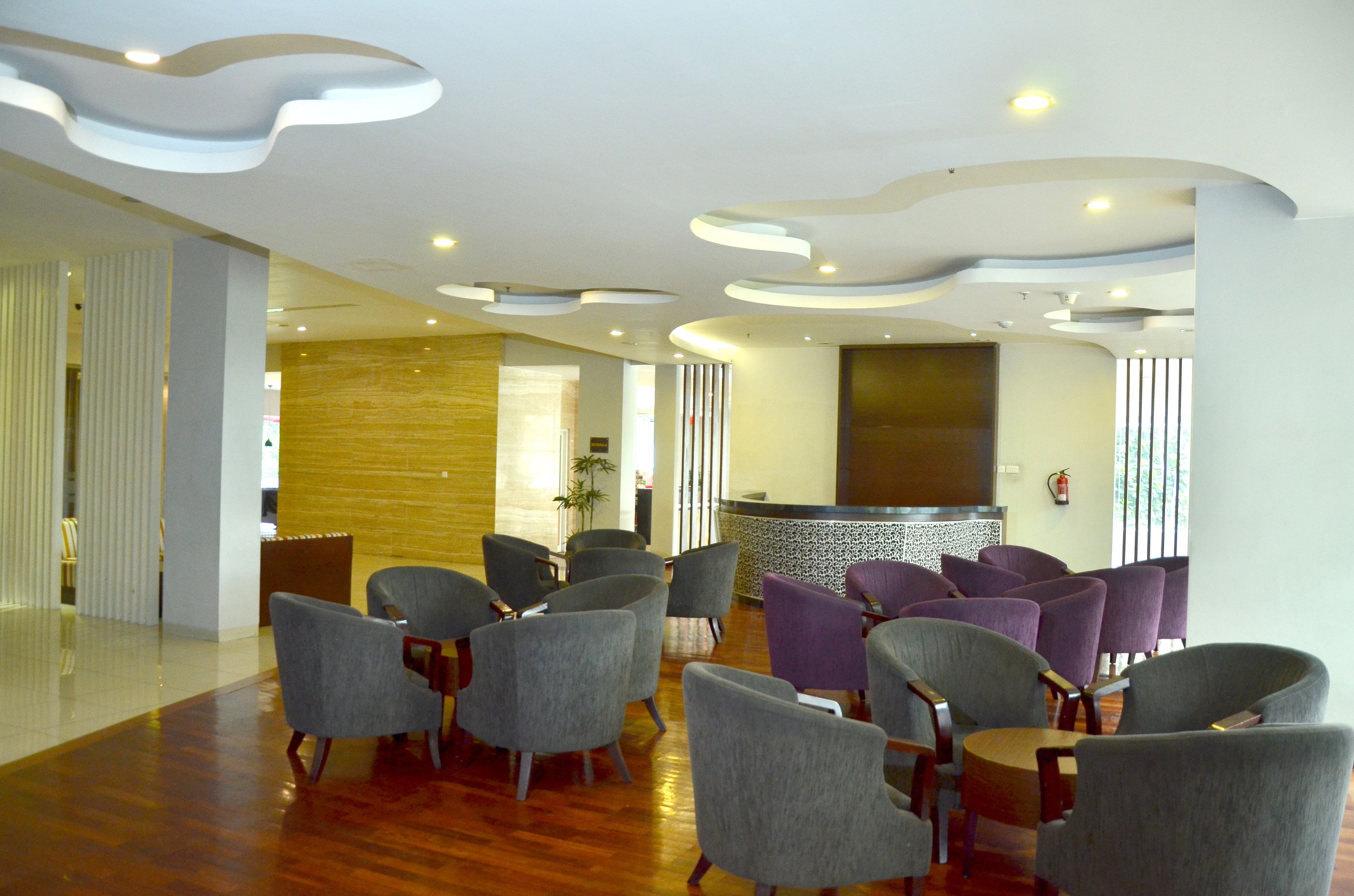 A modern lobby with a reception desk, grey and purple seating, and a wooden floor.