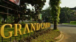 A large outdoor sign with the words "GRAND CARRI" in gold letters, surrounded by greenery and trees. - Grand Cakra Hotel (Malang)
