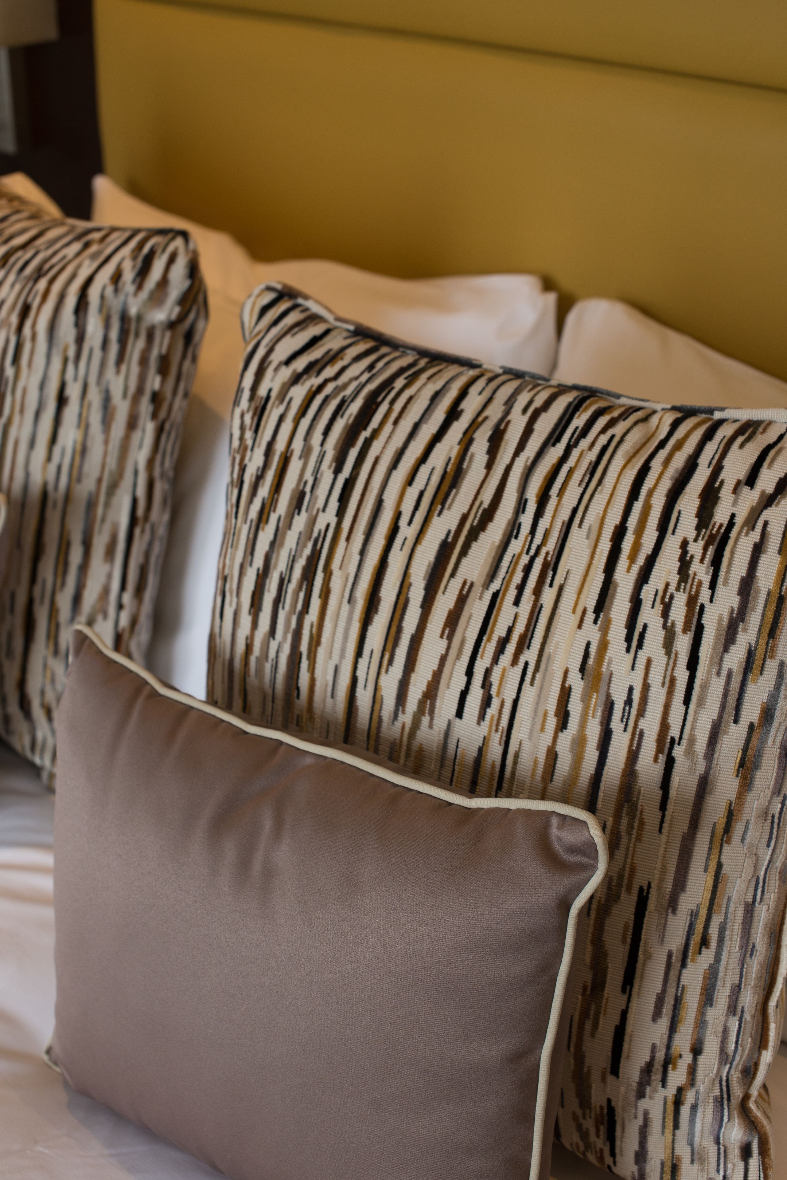 A bed with patterned pillows and a plain pillow.