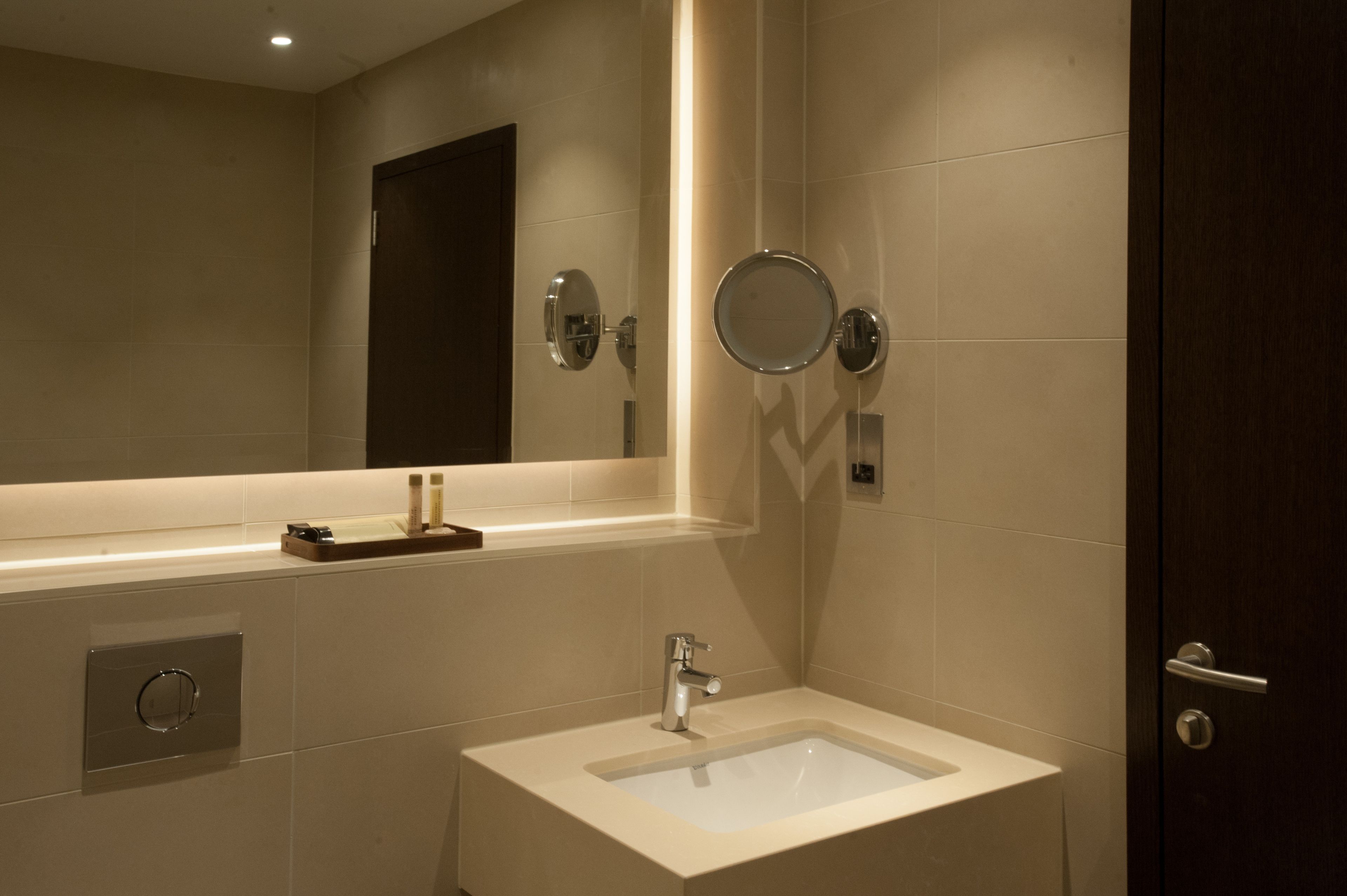 A modern bathroom with a large mirror, a sink, and a door.
