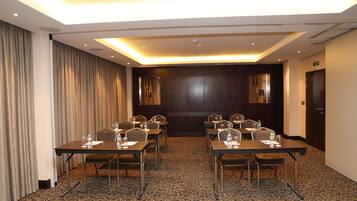A conference room with a long table, chairs, and a carpeted floor.