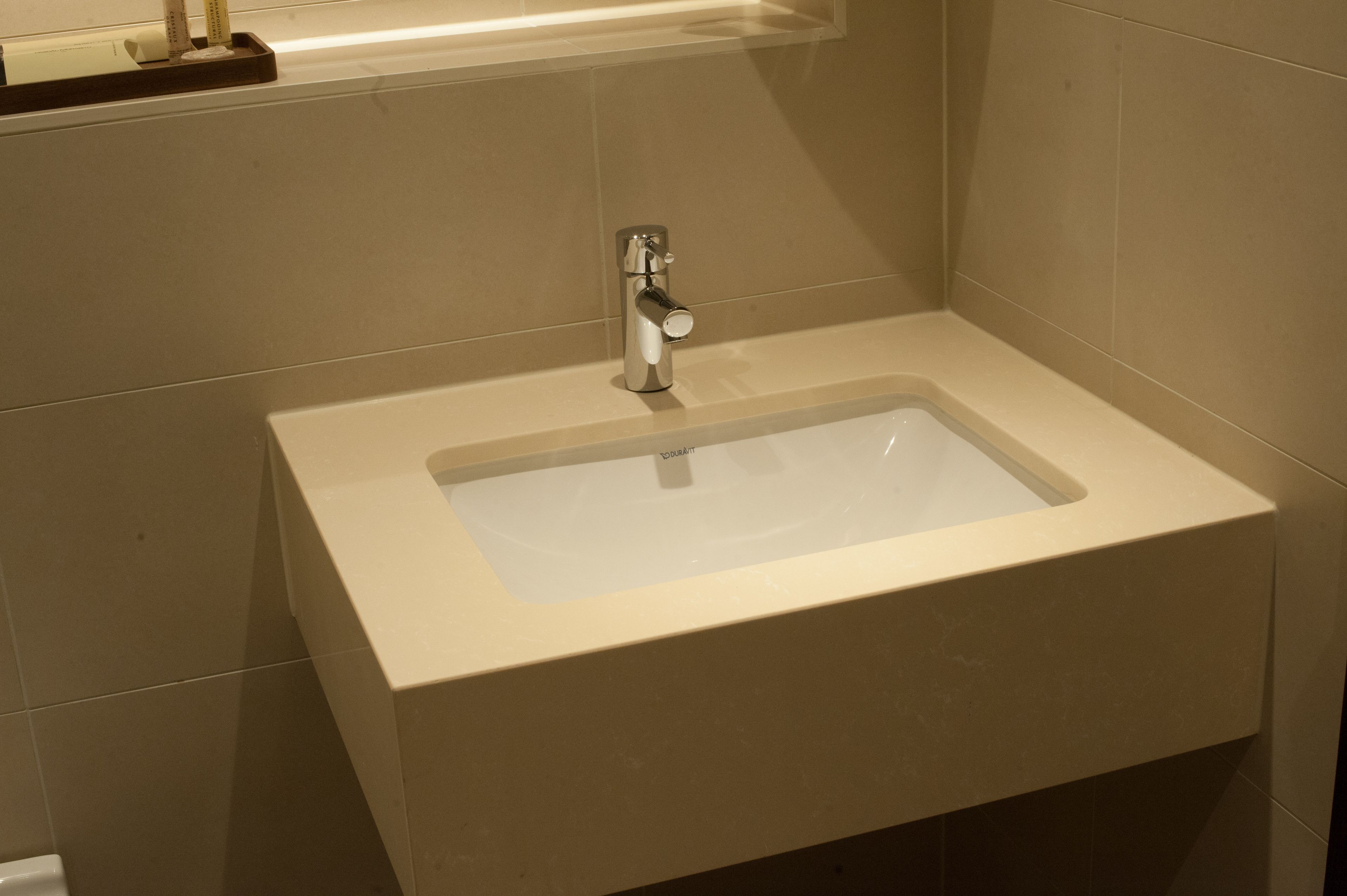 Un baño con un lavamanos rectangular, un grifo y un espejo encima.