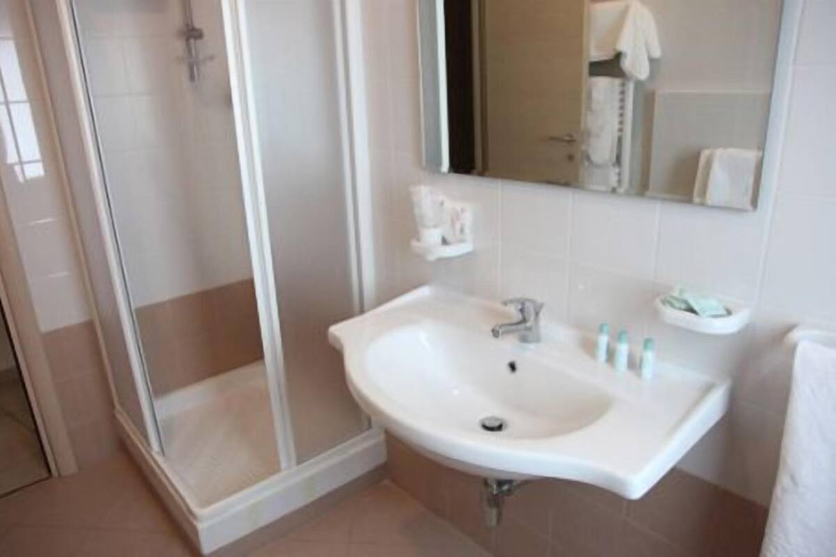 A bathroom with a white sink, a mirror, and a shower area.