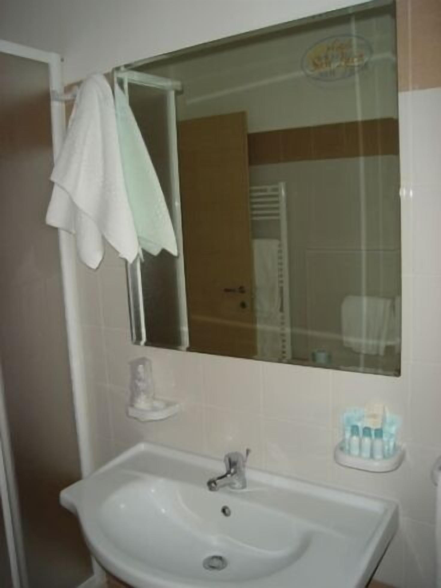 Un baño con un lavabo blanco, un espejo y una toalla colgada en la pared.
