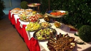 A buffet table with various dishes, including salads, meats, and vegetables, set outdoors.