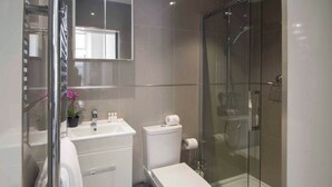 Un bagno moderno con cabina doccia in vetro, lavabo bianco e water.
