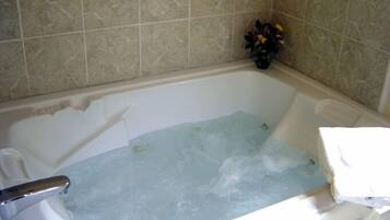 Una bañera con agua, un florero y una toalla sobre una superficie blanca.