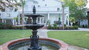 A white house with a brick fountain in the front yard.