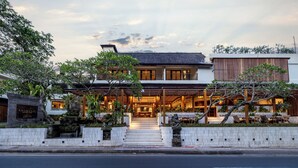 A modern hotel with a stone facade, a staircase leading to the entrance, and outdoor seating. - Anumana Ubud Bali (Ubud)