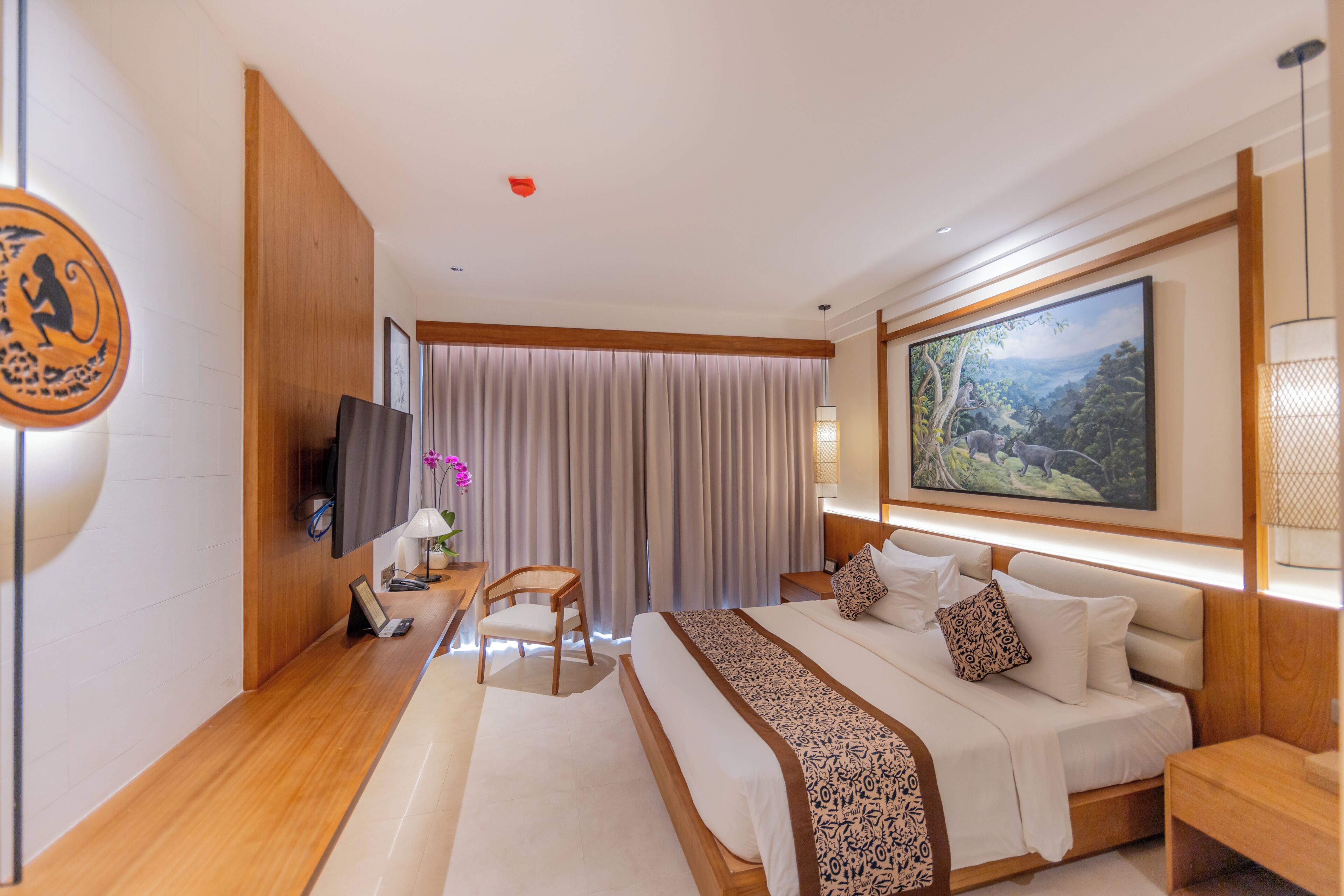 A hotel room with a bed, a desk, a chair, a TV, and a painting on the wall.