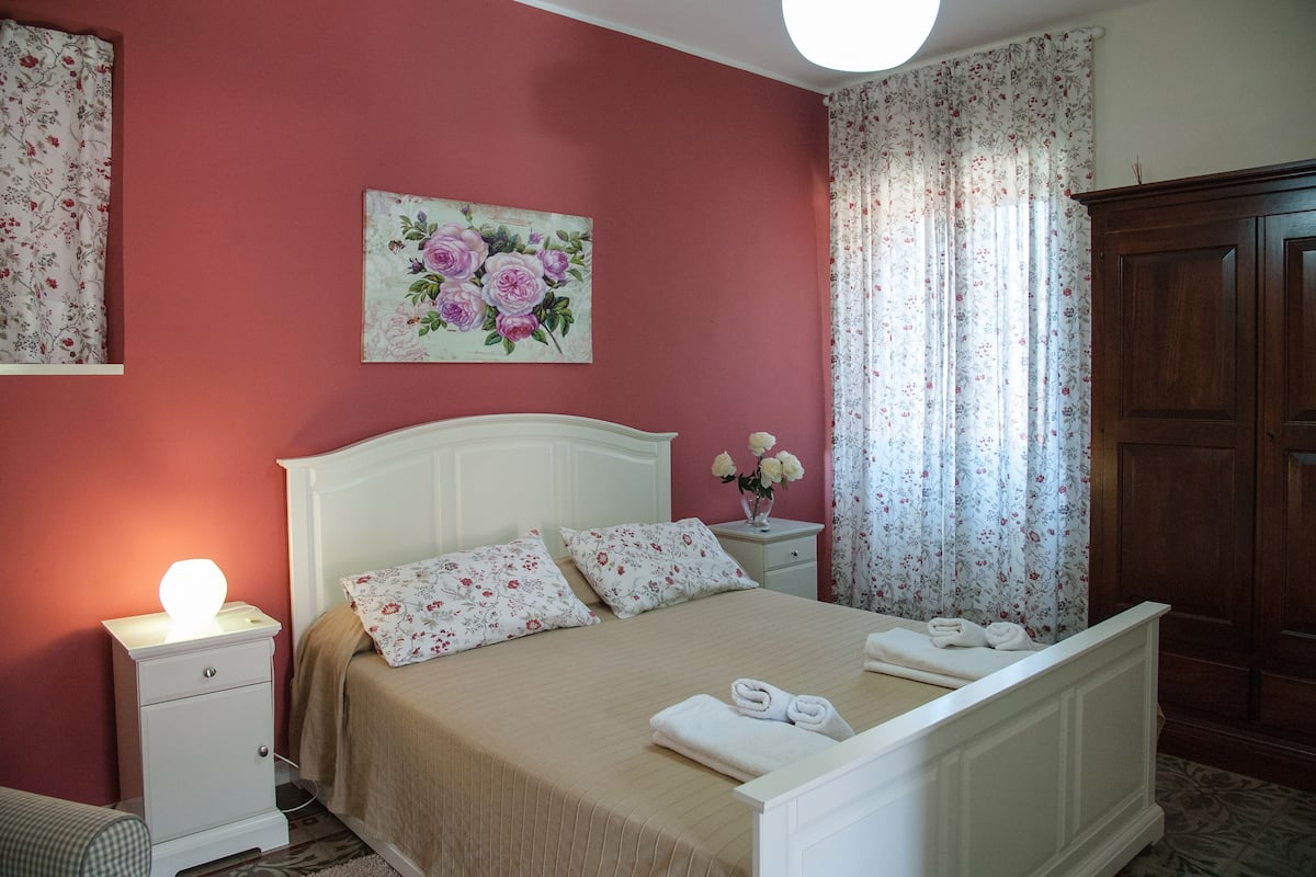 A bedroom with a bed, nightstand, and a wooden wardrobe.