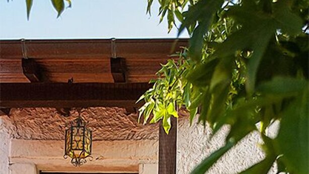 A building with a stone facade, a wooden balcony, and a hanging lantern. - B&B A Corte (Caserta)