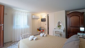 A hotel room with a large bed, a desk, a chair, a TV, and a wardrobe. - B&B A Corte (Caserta)