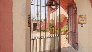 An arched entrance with a metal gate, a sign reading "A CORTE b&b", and a courtyard with potted plants. - B&B A Corte (Caserta)