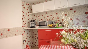 A compact kitchen with a red and white checkered tablecloth, a microwave, a toaster, and a coffee maker on the countertop. - B&B A Corte (Caserta)