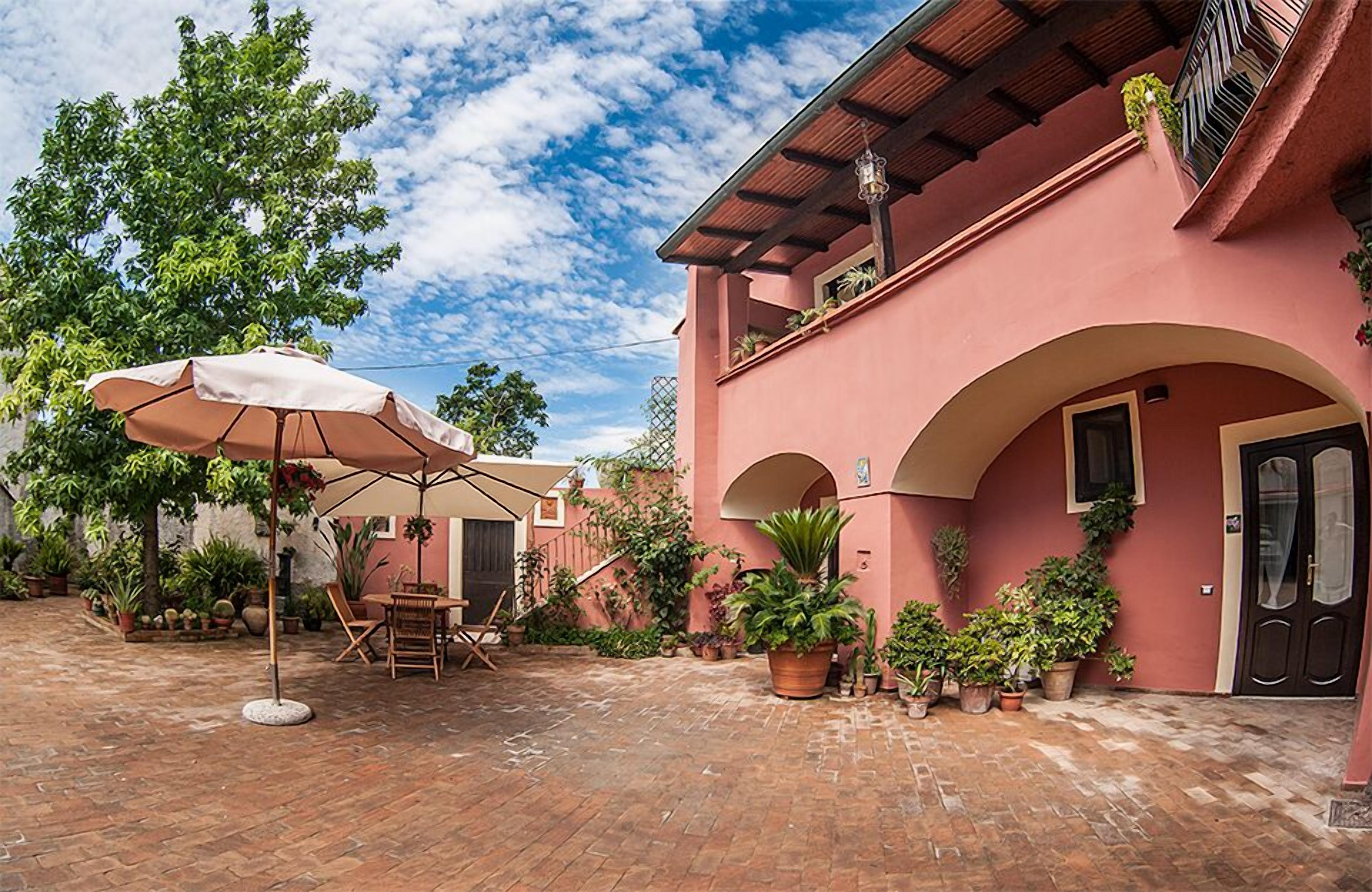 A courtyard with a brick floor, outdoor furniture, and potted plants.
