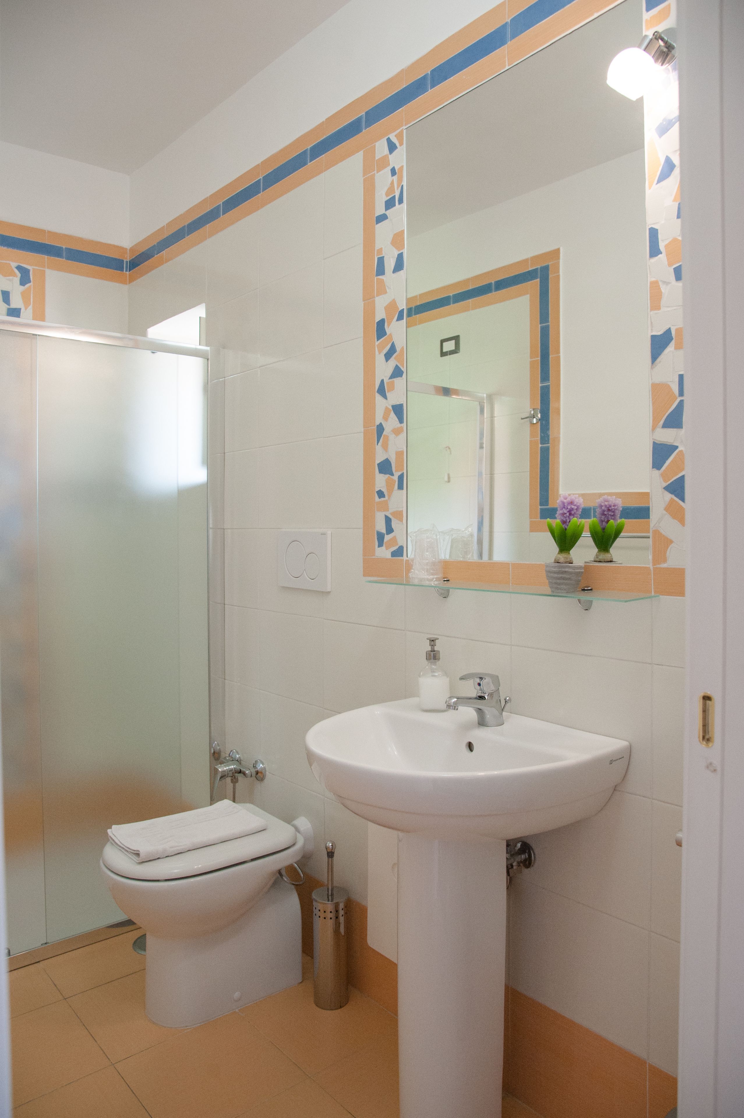 A bathroom with a toilet, sink, and a glass shower enclosure.