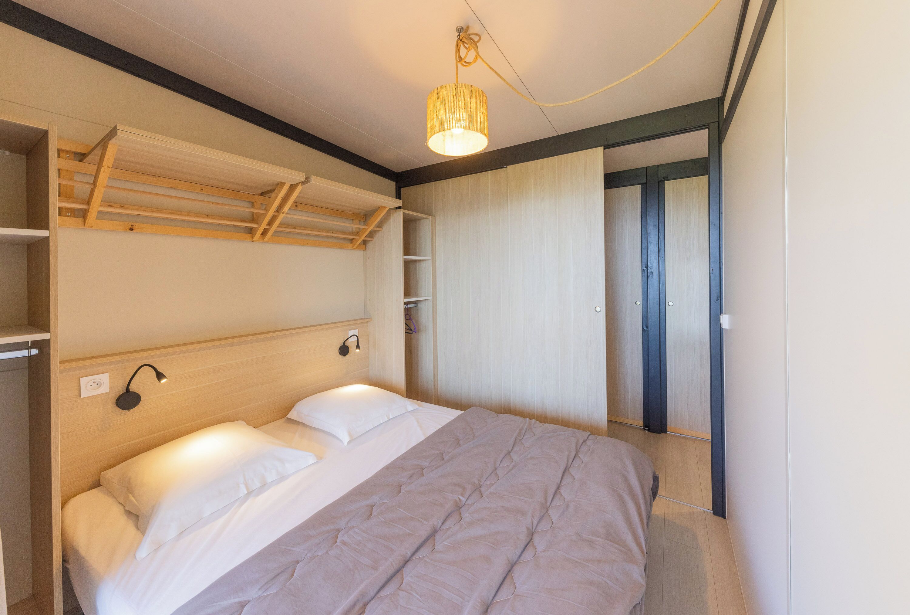 Een slaapkamer met een bed, een hanglamp en een kledingkast.