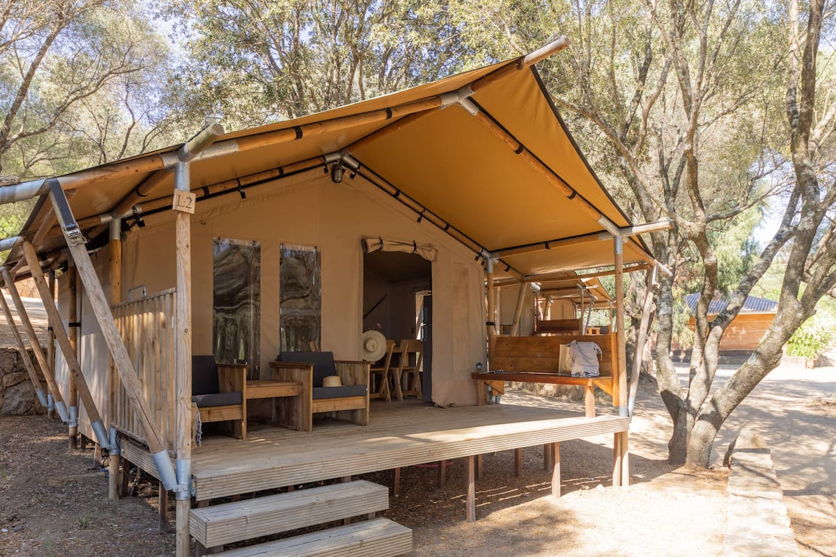 Une tente dotée d’une terrasse en bois, d’un espace salon et d’un banc.