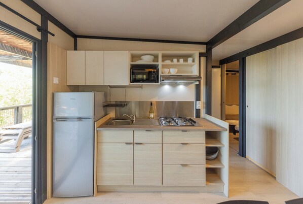 A compact kitchen with a built-in refrigerator, a microwave, and a gas stove.