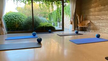 Una habitación amplia con ventanas grandes, colchonetas de ejercicio y balones de pilates.