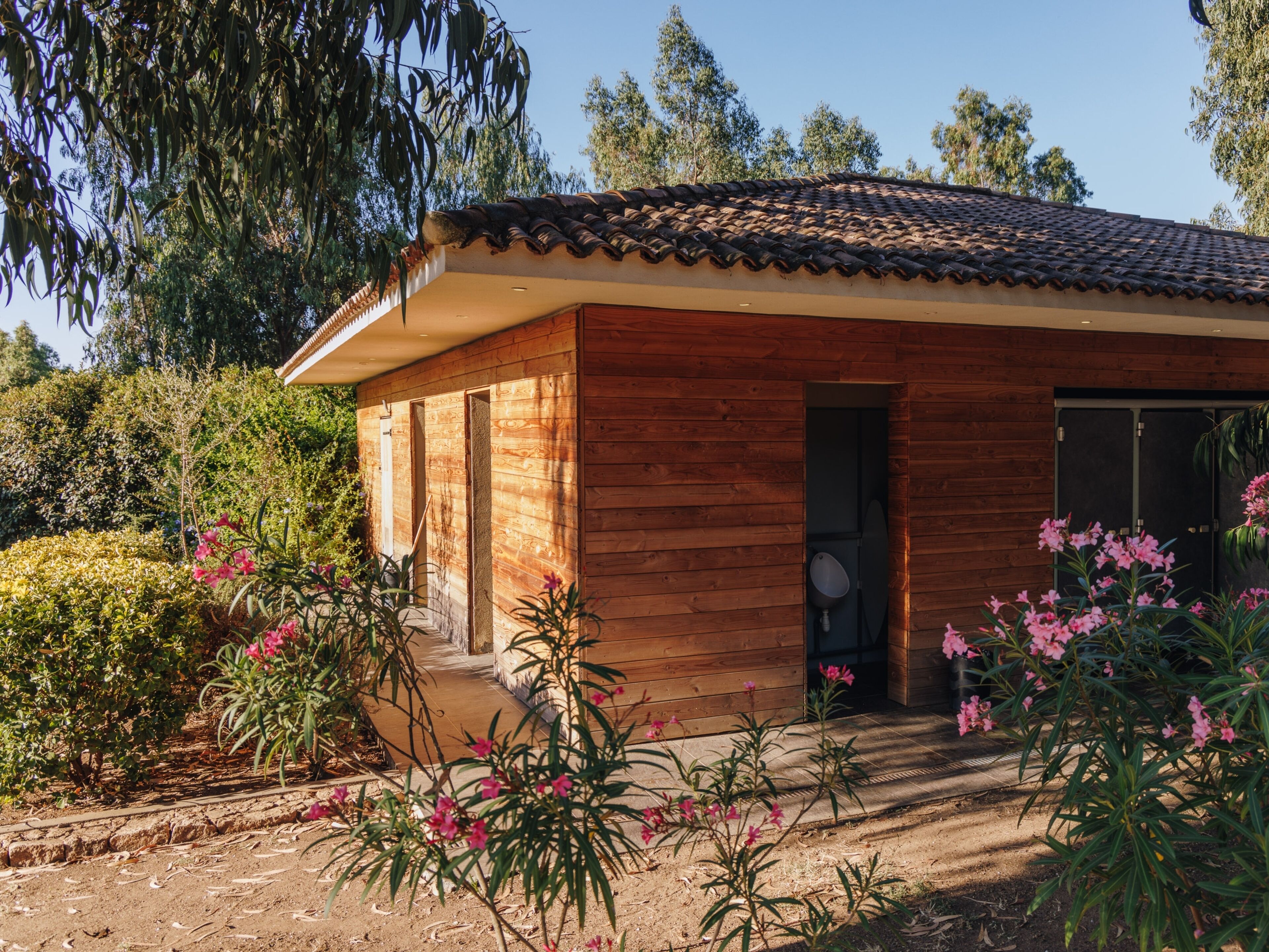 A wooden house with a tiled roof, a front door, and a small porch area.
