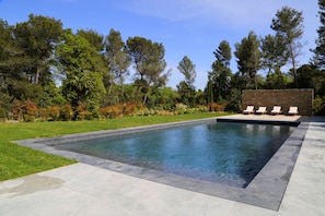 A rectangular swimming pool with a stone border, surrounded by a well-maintained lawn and trees. - Domaine Rampale (Fuveau)