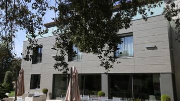 Un bâtiment moderne doté d’un patio aménagé avec du mobilier d’extérieur et des parasols.