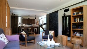 A modern living room with a sofa, chairs, a coffee table, and a bookshelf. - Domaine Rampale (Fuveau)