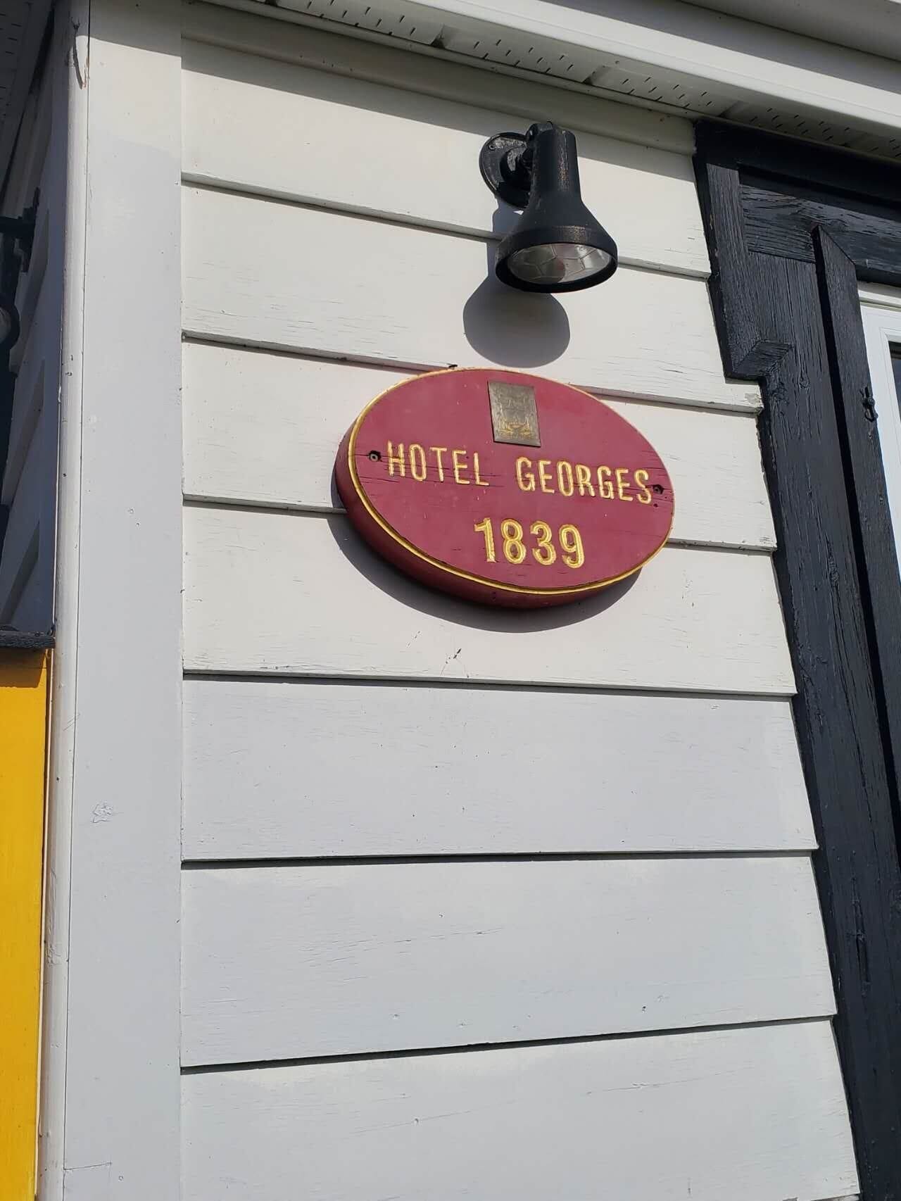 A red plaque on a white wall with the text "HOTEL GEORGES 1839".