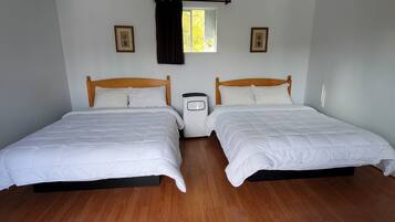 A double room with two beds, a window with curtains, and a bedside table.