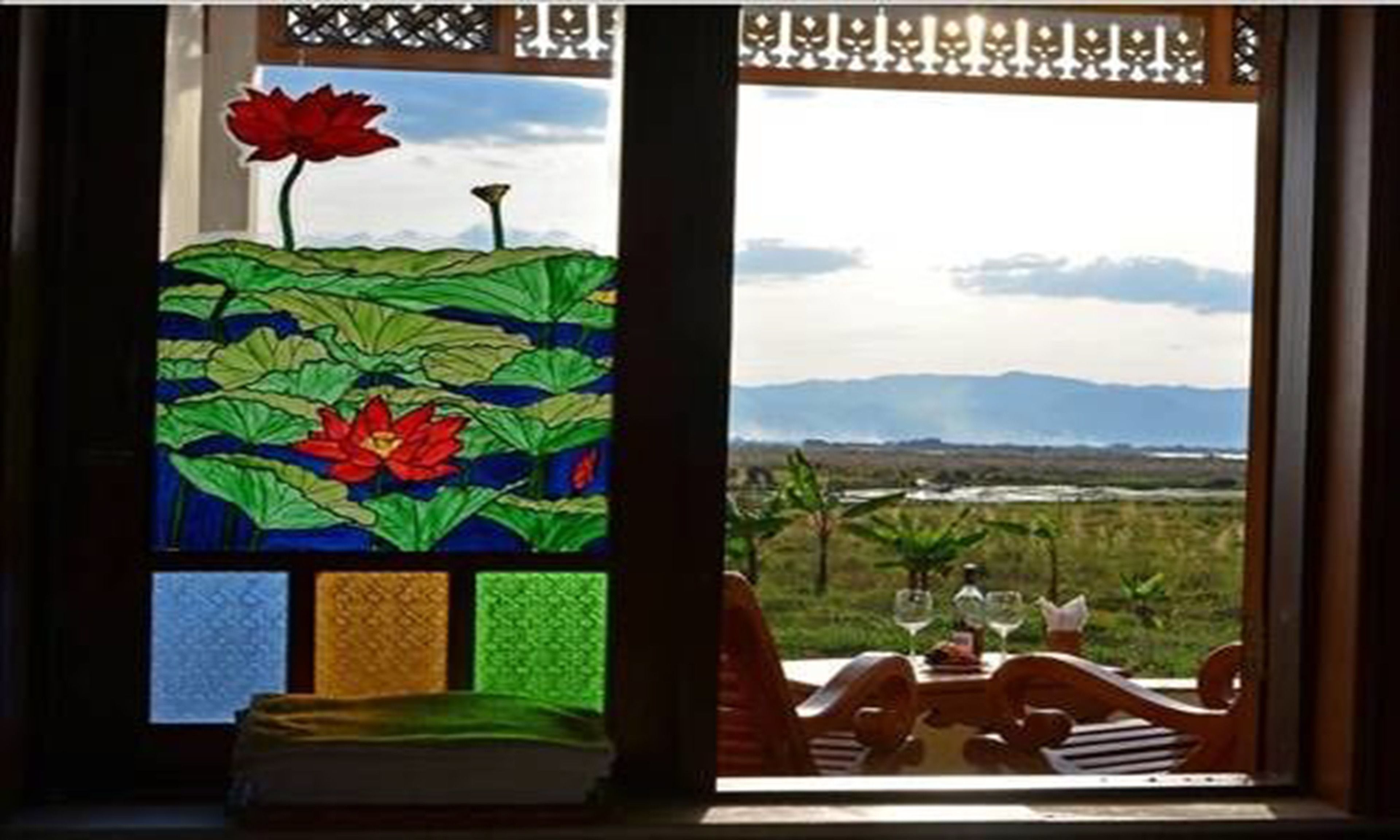 A dining area with a table set for two, overlooking a landscape with mountains.